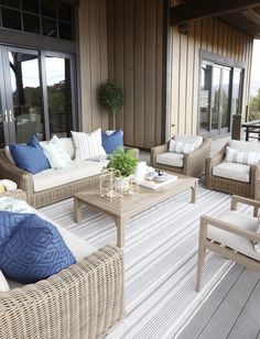 an outdoor living room with wicker furniture and blue pillows on the couches outside