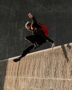 a man riding a skateboard up the side of a wall with his hands in the air