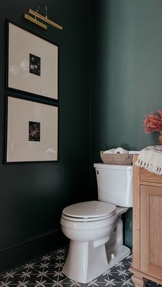 a white toilet sitting in a bathroom next to a wooden cabinet and flower vase on top of it