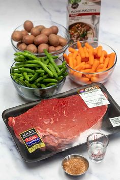 raw meat, vegetables and seasoning on a counter top with ingredients for the recipe