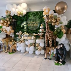 a giraffe and other animals are on display in front of balloons, greenery, and decorations