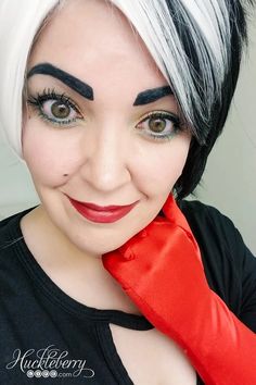 a woman with black and white hair is wearing red gloves while smiling at the camera