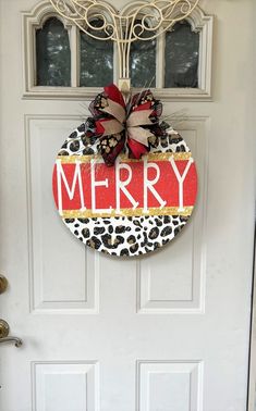 a leopard print door hanger with the word merry on it, and a bow