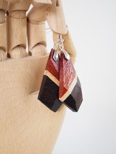 These unique earrings are made by layering a variety of wood species to create designs which highlight the beauty of the natural colors and grain patterns. They're shaped and faceted by hand, then finished with shellac for a durable shine. The hooks are made from 925 sterling silver. These earrings measure approximately 2.5 inches long and weigh a total of 9 grams. Artisan Brown Wooden Earrings, Artisan Brown Wood Earrings, Brown Wooden Earrings As Gift, Unique Brown Wooden Earrings, Unique Natural Wood Earrings, Handmade Brown Geometric Earrings, Brown Geometric Earrings As Gift, Brown Geometric Earrings Gift, Camano Island