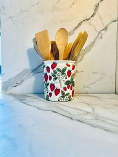 a cup with spoons and wooden utensils in it on a marble counter