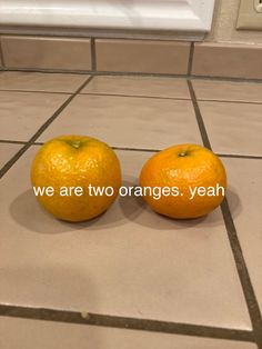 two oranges sitting on top of a tiled floor