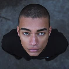 an overhead view of a man's face with blue eyes and black hoodie