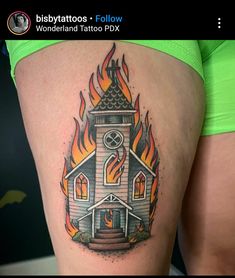 a woman's thigh with a small tattoo of a church on fire and flames