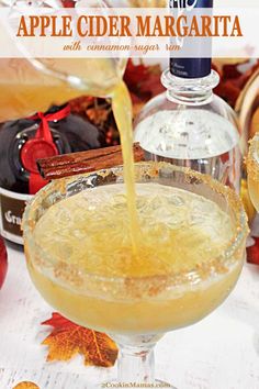 an apple cider margarita with cinnamon sugar being poured into the glass for garnish