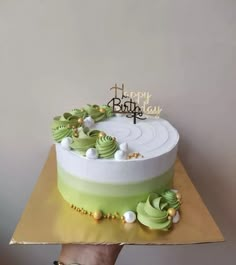 a birthday cake with green frosting and gold decorations