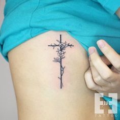 a cross and flowers tattoo on the side of a woman's ribcage