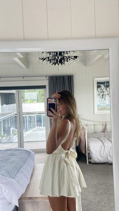 a woman is taking a selfie in front of a mirror with her reflection on the bed