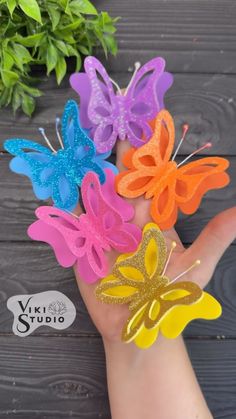 small butterfly hair clips in assorted colors on a person's hand next to flowers