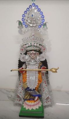 an idol is displayed in the corner of a room with white walls and marble flooring