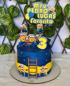 a three tiered cake decorated with minion characters and the number 3 on top