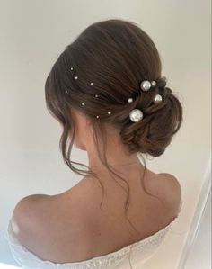 a woman with her hair in a low bun and pearls on the top of her head