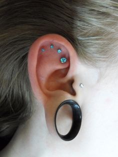 a person with an ear piercing made to look like a ring and has blue flowers on it