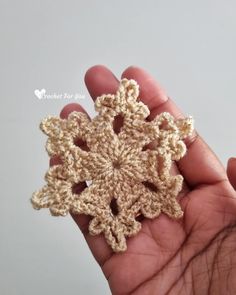 a crocheted snowflake is shown in the palm of someone's hand