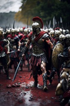 a large group of men dressed in roman armor and helmets walking down a muddy road