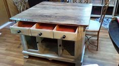 a kitchen table with drawers and chairs in the background