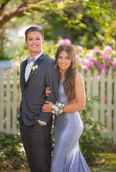 a young man and woman in formal wear posing for a photo outside on their wedding day