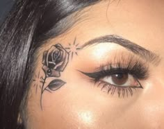 a close up of a woman's face with a rose tattoo on her forehead