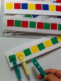 two pieces of colored tape are being held by someone's hand with scissors in front of them