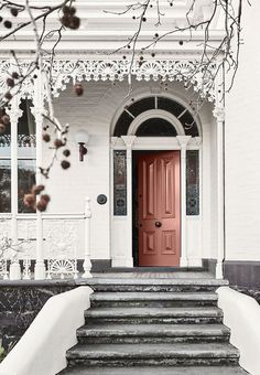 a red door sits in front of a white house with steps leading up to it