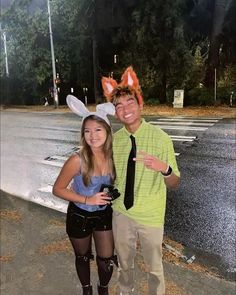 a man and woman in bunny ears posing for a photo on the street at night