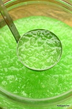 a glass bowl filled with green liquid and a ladle full of liquid on top