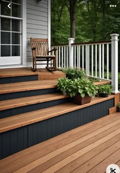 a porch with wooden steps and planters on it