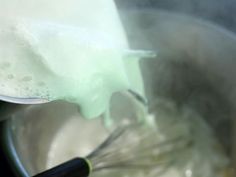 a whisk is being stirred in a saucepan with water and ice cream