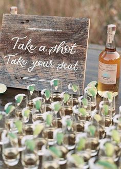 there are many shot glasses on the table with a sign that says take a shot, take your seat