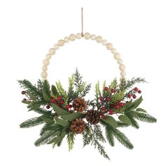 a christmas wreath with pine cones, berries and greenery hanging from a string on a white background