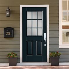 a black front door on a house with two planters next to it and a mailbox