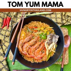 a bowl filled with noodles and shrimp next to chopsticks on top of a green leaf