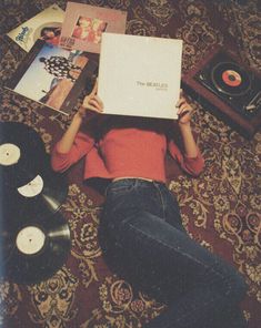 a woman is laying on the floor holding up a record box