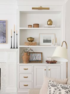 a living room filled with white furniture and lots of gold accessories on top of it