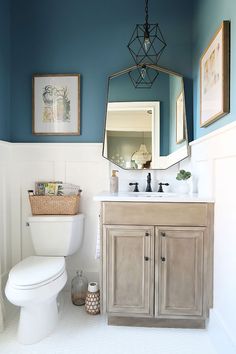 a white toilet sitting under a bathroom mirror next to a wooden sink vanity in a bathroom