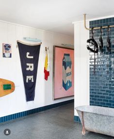 there is a bathtub in the bathroom with surfboards hanging on the wall next to it