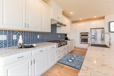 a kitchen with marble counter tops and white cabinets