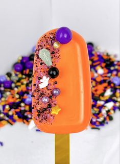 an orange popsicle covered in sprinkles and beads