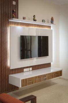 a flat screen tv mounted to the side of a white wall in a living room