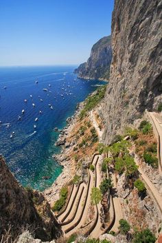 stairs leading down to the beach with boats in the water and cliffs on either side