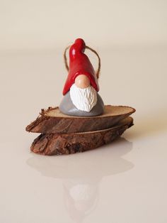 a gnome figurine sitting on top of a piece of wood with a red hat