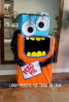 an orange and blue monster costume sitting in front of a mirror with the words candy monster for trunk or treat on it