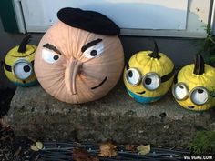 three pumpkins with faces painted on them sitting in front of a door and some plants