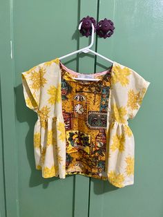 a yellow and white top hanging on a green door