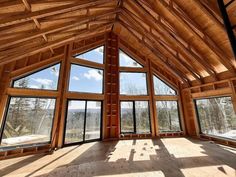 an empty room with large windows and wood framing on the ceiling is seen in this image