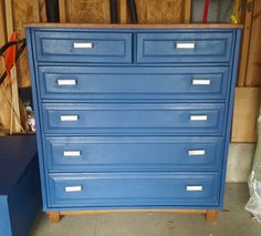 a blue dresser sitting in a garage next to some tools